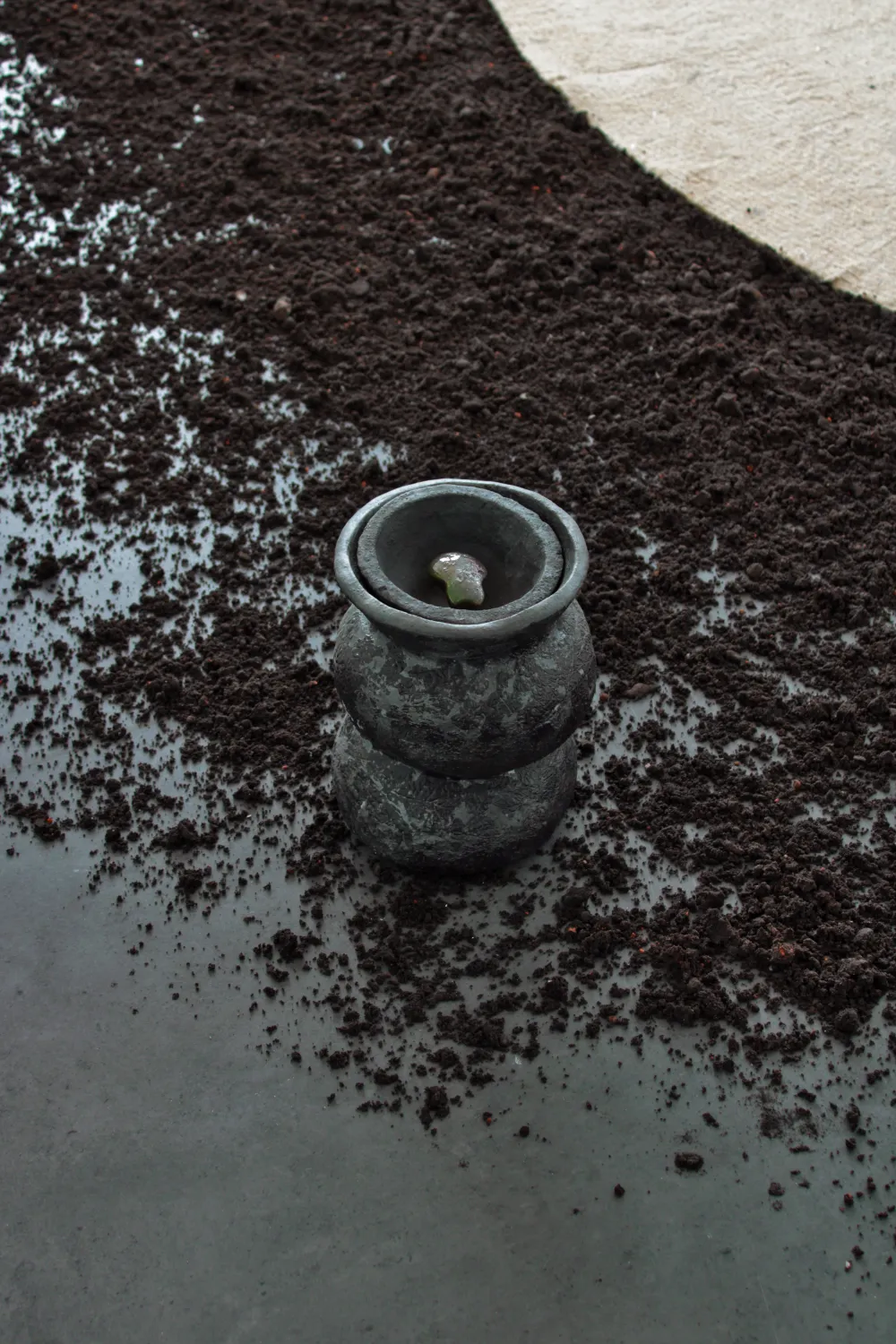 Ceramic vessel on dark earth, installation view