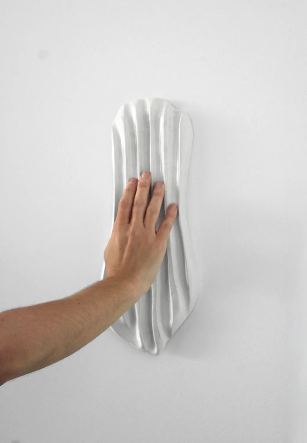 Hand touching ribbed plaster wall relief sculpture