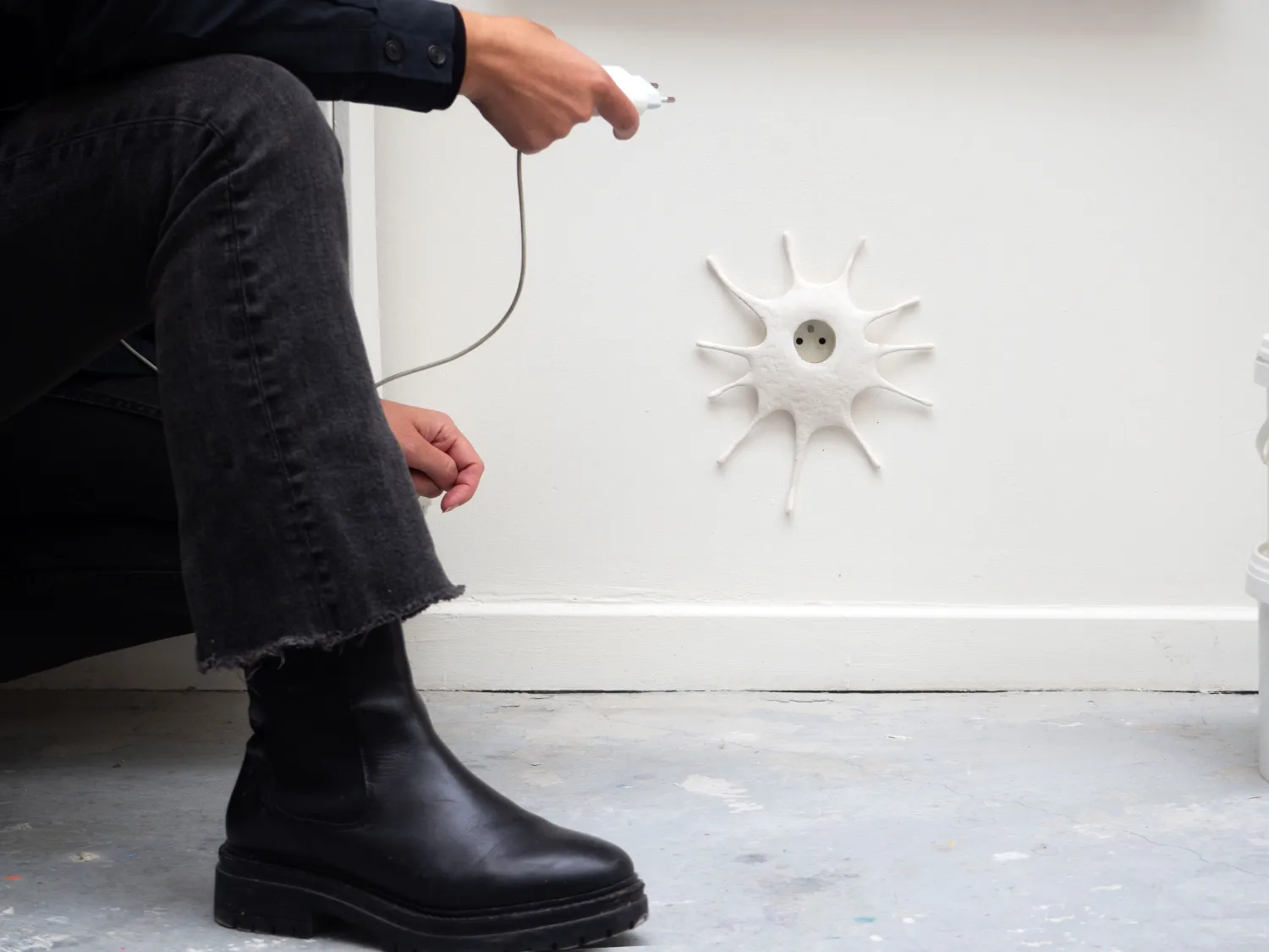Sun-shaped plaster sculpture around electrical socket, studio Paris