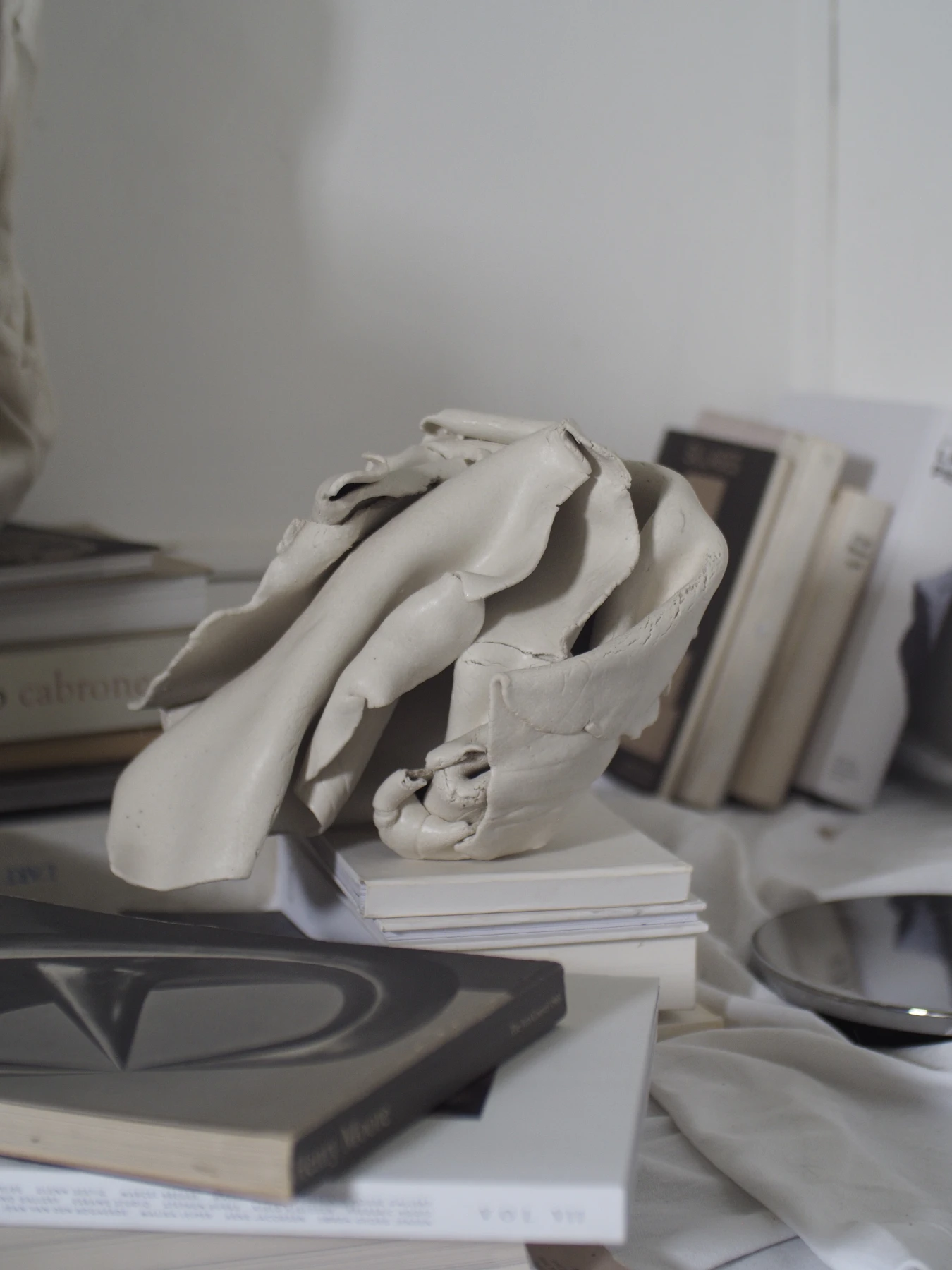 Porcelain piece resting beside stacked art books