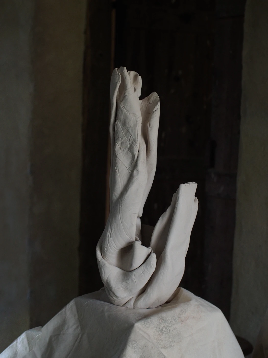 Tall elongated porcelain sculpture against a dark stone doorway