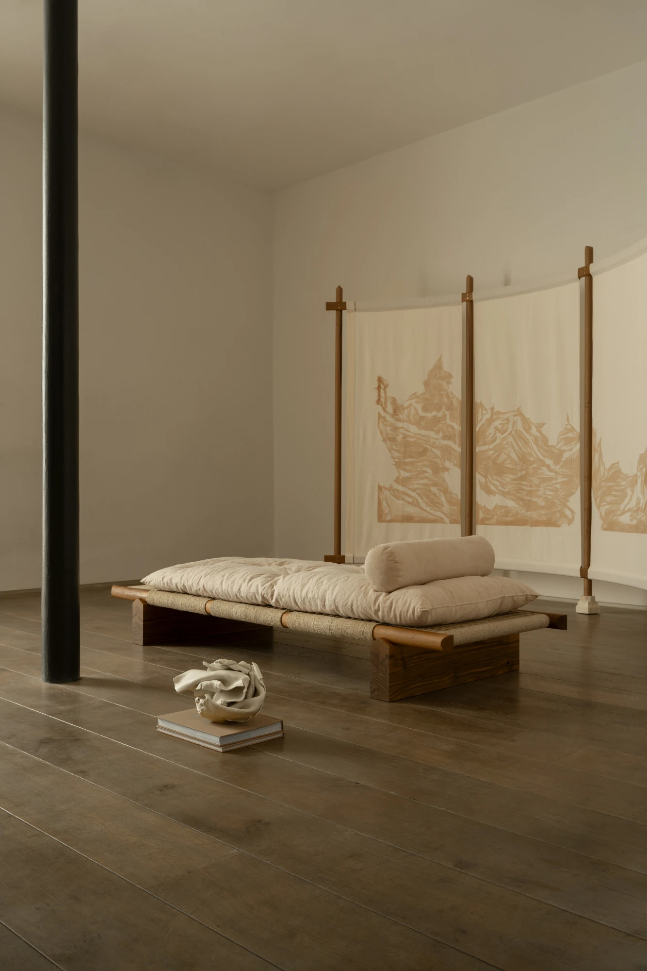 Ceramic sculptures placed around a daybed in a gallery setting