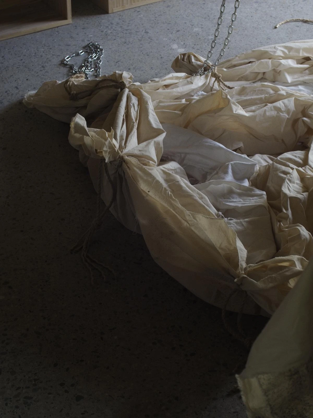 Large canvas textile wrapping with tied knots on a studio floor